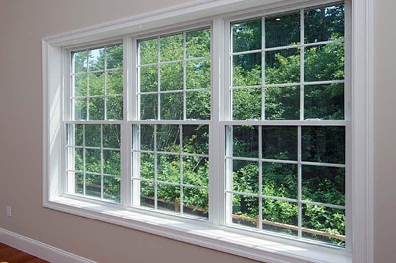 White-framed windows overlooking a green yard