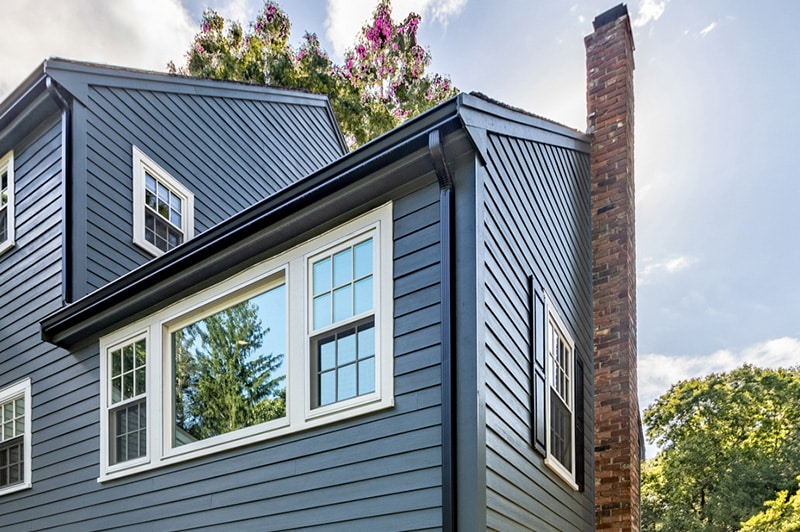 Blue exterior siding with white window trim and a brick chimney