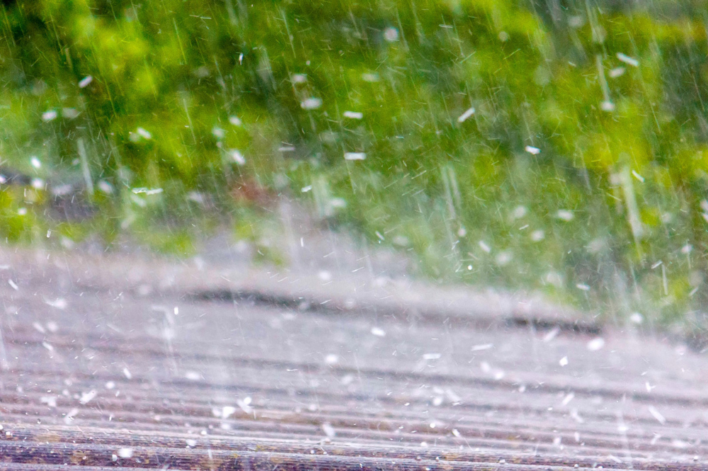 A hail storm hitting a roof highlights impact-resistant roofing, ensuring safety and durability.