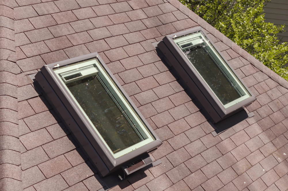 Two skylights installed in a shingle roof, showing the surrounding flashing