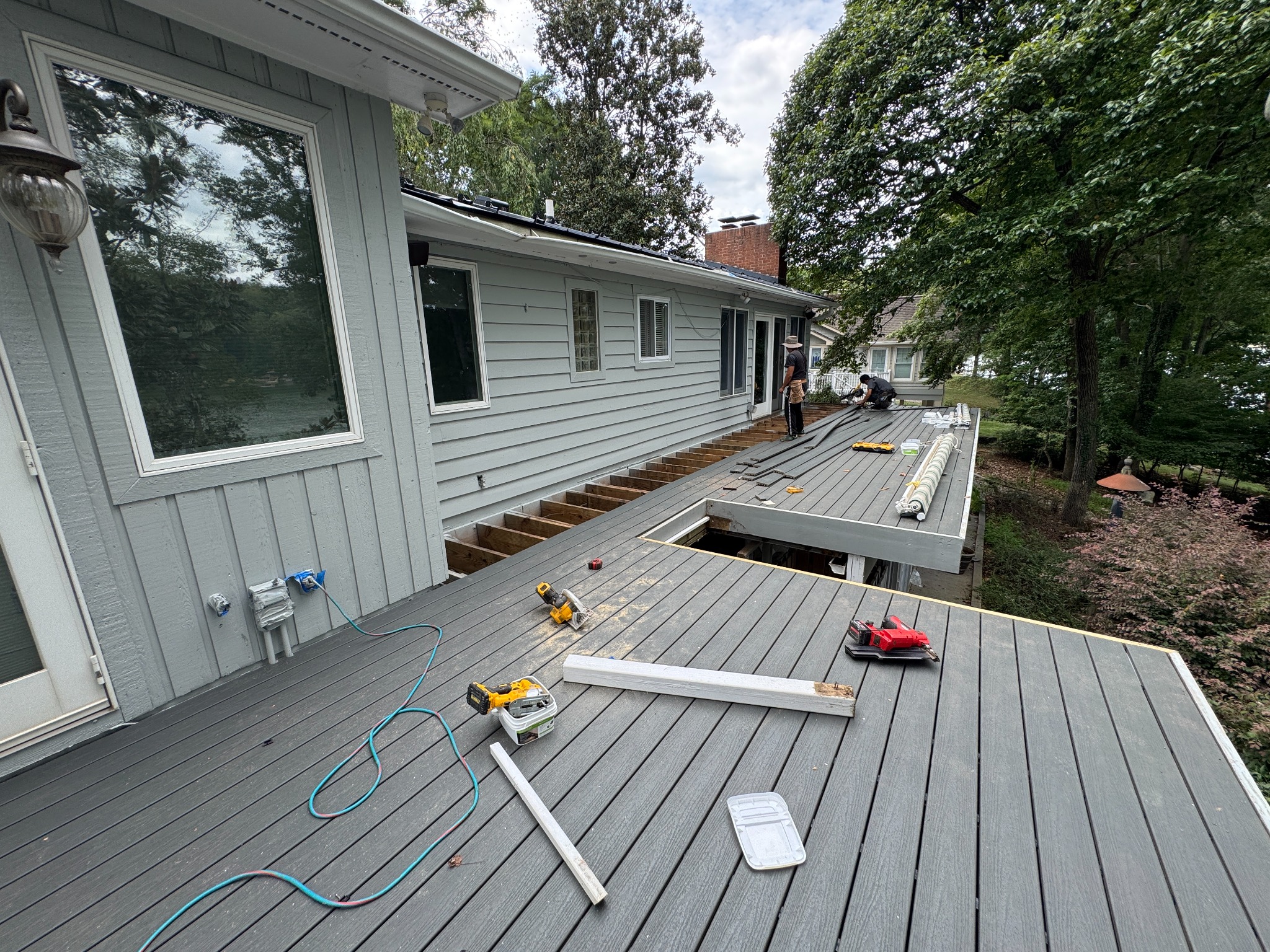 Gray deck boards being installed beside a home